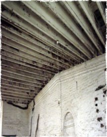 Roof supported by wooden beams and board.